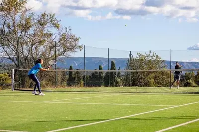 two people playing tennis on a tennis court at La Calade in LʼIsle-sur-la-Sorgue