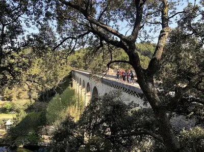 a group of people walking on a bridge at La Calade in LʼIsle-sur-la-Sorgue