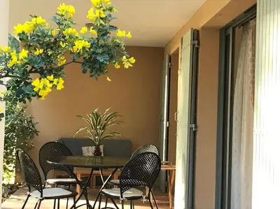 a patio with a table and chairs and yellow flowers at La Calade in LʼIsle-sur-la-Sorgue