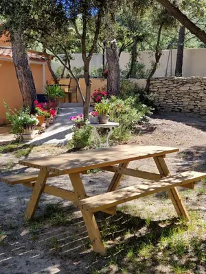 a wooden picnic table in a park with flowers at la Cigalière in LʼIsle-sur-la-Sorgue