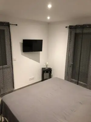 a bedroom with a bed and a flat screen tv on the wall at Pitchoun in Velaux