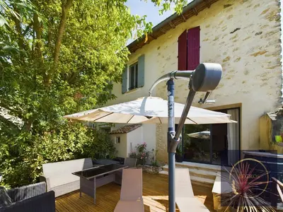 a patio with a table and an umbrella at La terrasse du pêcheur in LʼIsle-sur-la-Sorgue
