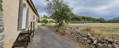 a path next to a stone wall next to a building at maison O jasmin in Lagnes