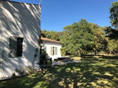 a white house with a yard next to a building at Proche Aix-en-Provence maison avec piscine - 10 personnes in Rognes