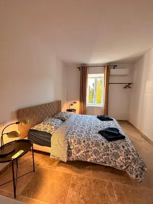a bedroom with a bed and a table and a window at Maison : L'Appart des Anges 10 personnes in Althen-des-Paluds