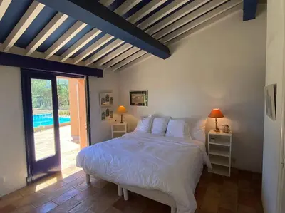 a bedroom with a large bed and a pool at Villa Les Gourdeaux in Roussillon