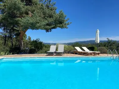 a swimming pool with two chairs and an umbrella at Villa Les Gourdeaux in Roussillon