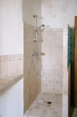 a shower in a bathroom with a tile floor at Charming Village House in the Heart of Isle-sur-la-Sorgue in LʼIsle-sur-la-Sorgue