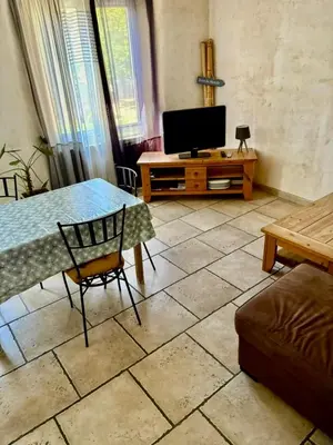 a living room with a table and a television at Charming Village House in the Heart of Isle-sur-la-Sorgue in LʼIsle-sur-la-Sorgue