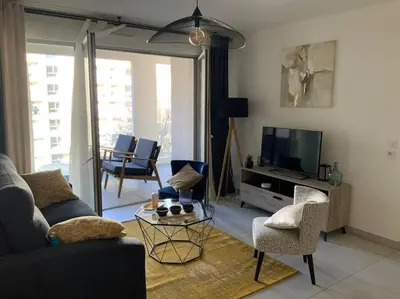 a living room with a couch and chairs and a tv at Logement cosy climatisé avec parking in Aix-en-Provence