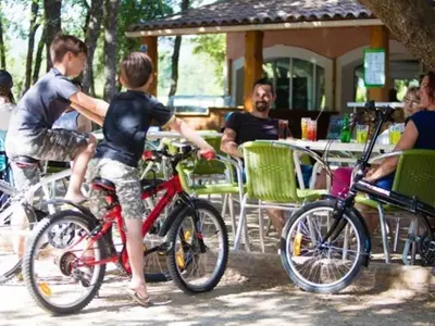 two young boys on their bikes at a restaurant at Camping maeva Escapades Le Domaine des Chênes Blancs in Croagnes