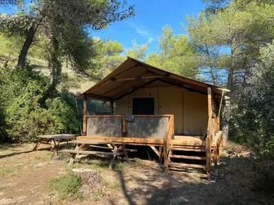 a wooden tent with a table in a forest at Camping maeva Respire La Vallée Heureuse in Orgon