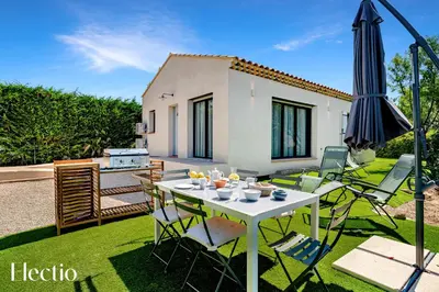 a patio with a table and chairs and an umbrella at Villa Oliveda - Piscine & Salon Cinéma in Lourmarin