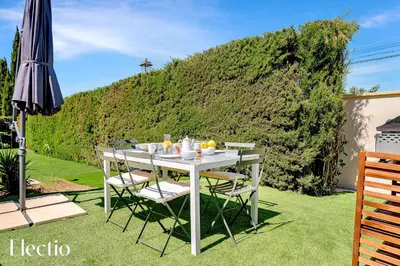 a white table with chairs and an umbrella on the grass at Villa Oliveda - Piscine & Salon Cinéma in Lourmarin