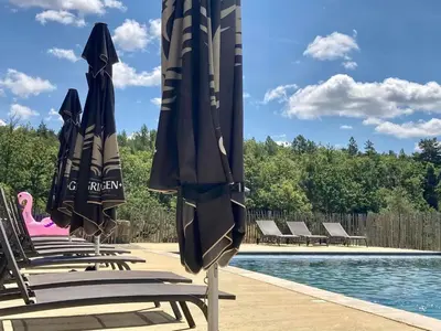 a group of chairs with umbrellas next to a pool at La Grisonne - Gîte Camus in Revest-du-Bion
