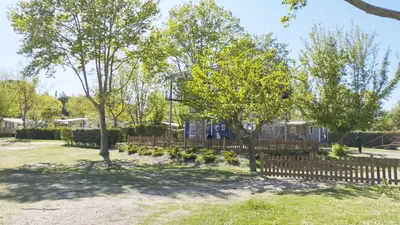 a ferris wheel in a park with a wooden fence at Mobil Home vue sur le lac dans un camping 4 étoiles à Cadenet in Cadenet