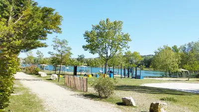 a path next to a park with a playground at Mobil Home vue sur le lac dans un camping 4 étoiles à Cadenet in Cadenet