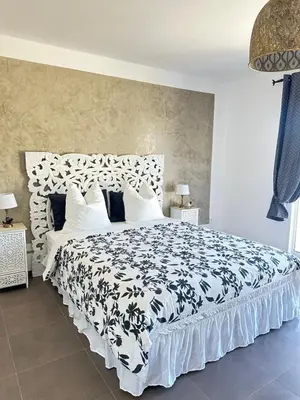 a bedroom with a large bed with a black and white comforter at Magnifique villa familiale avec piscine in Caumont-sur-Durance