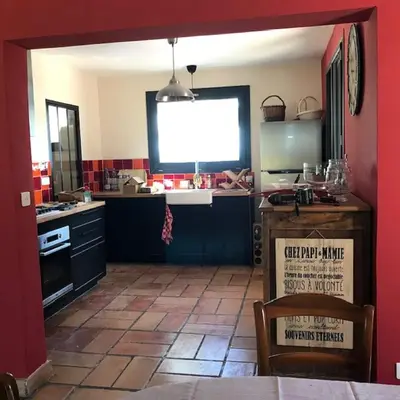 a kitchen with a red wall and a kitchen with a table at Gîte de L'Embuissonnade in Montfuron