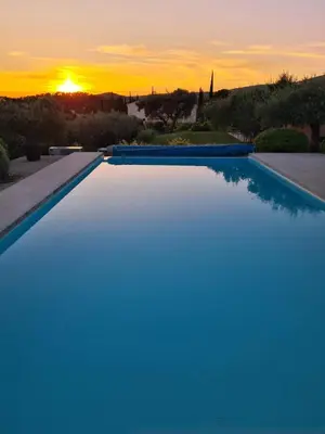 a swimming pool with a sunset in the background at Villa jeanne avec piscine Chauffée à Bedoin in Bédoin