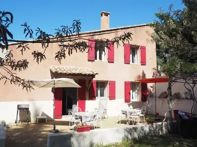 a building with red shutters and tables and chairs at Holiday Home in Provence near Mont Ventoux in Bédoin