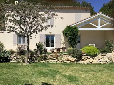 a house with a stone wall and a tree in the yard at PERNO LI FONT villa contemporaine avec piscine in Pernes-les-Fontaines