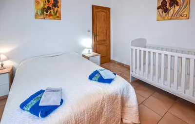 a bedroom with a white bed with two towels on it at Les Romarins dans le Mas de la PERRINE entre AVIGNON LUBERON Mt VENTOUX in Monteux