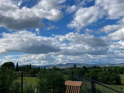 a chair sitting on a fence with a cloudy sky at Maison au pied du mont ventoux in Carpentras