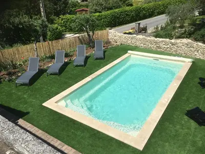 a swimming pool with lawn chairs and a swimming pool at Les Juliens in Gordes