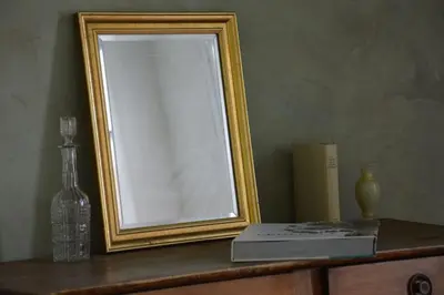 a mirror sitting on top of a dresser with a book at La loge familiale: 110m2, place rose goudard, AC in LʼIsle-sur-la-Sorgue