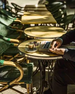 a person is sitting at a table with a laptop at La loge familiale: 110m2, place rose goudard, AC in LʼIsle-sur-la-Sorgue