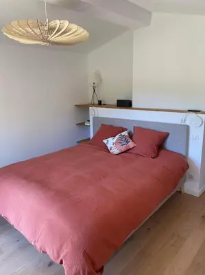 a bed with a red blanket and two red pillows at Magnifique Mas avec Piscine Luberon (Gordes) in Murs