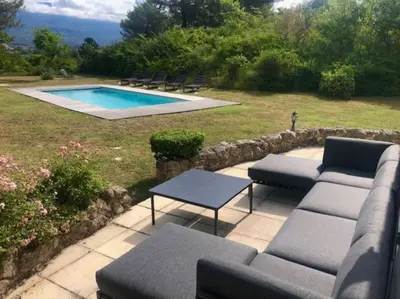 a patio with a couch and tables and a pool at Mazet avec piscine, vue Ventoux in Crillon-le-Brave