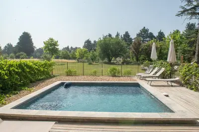 a pool in a yard with a deck and chairs at La palasse in Le Thor
