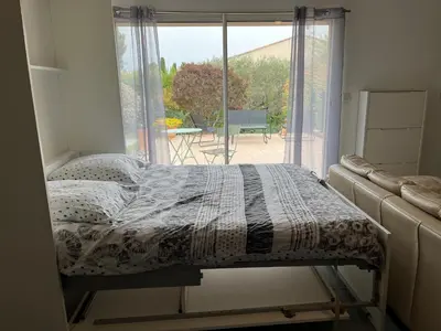 a bed in a room with a large window at Studio charmant avec terrasse in Lançon-Provence