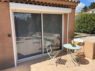 a sliding glass door with a table and chairs on a patio at Studio charmant avec terrasse in Lançon-Provence