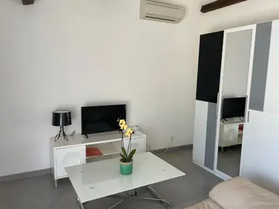 a white living room with a table and a tv at Studio charmant avec terrasse in Lançon-Provence