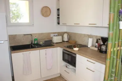 a kitchen with white cabinets and a clock on the wall at Gîte la Cigale en pleine campagne in Carpentras