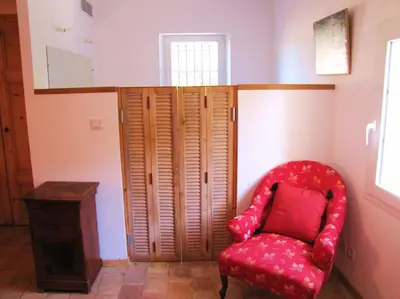 a red chair in a room with a wooden cabinet at LUBERON - AIR CONDITIONING VILLA - 4 BEDROOMS - 4 BATHROOM in Lourmarin