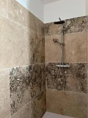 a bathroom with a shower with a stone wall at Villa charmante à Châteaurenard avec piscine privée in Châteaurenard