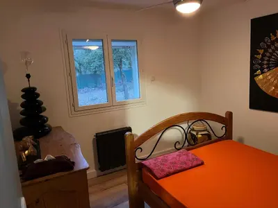 a bedroom with an orange bed and two windows at Villa dans la forêt provençale in Jouques
