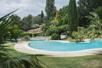 a large swimming pool in a yard with trees at Setclub Hôtel & Spa Aix-en-Provence in Aix-en-Provence