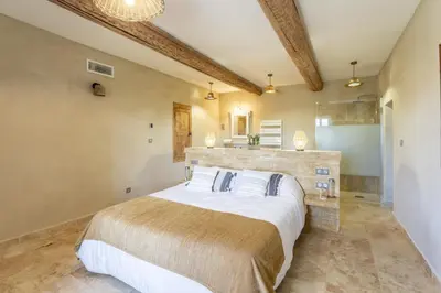 a bedroom with a large bed and a bathroom at Provencal farm with heated pool in Lamanon near Aix en Provence - 12 people in Lamanon