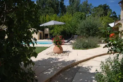 a garden with a pool and a vase of flowers at Typical farm with private pool close to the Ventoux 8 persons in Althen-des-Paluds