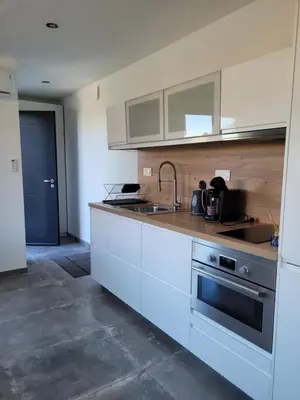 a kitchen with white cabinets and a sink and a stove at Gîte au pied du mont ventoux in Bédoin