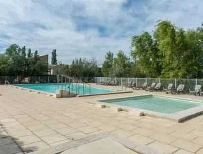 a swimming pool with chairs and a fence around it at T2 Résidence Sun Hols les Rives du Lac piscine, jardin in Saint-Saturnin-lès-Avignon