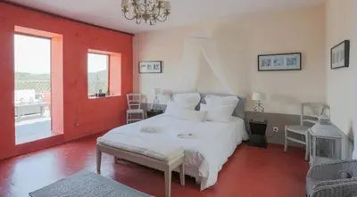 a bedroom with a white bed and a red wall at ELIA HOUSE in Goult