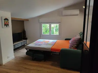 a bedroom with a bed and a window and a couch at Studio dans la forêt provençale in Jouques