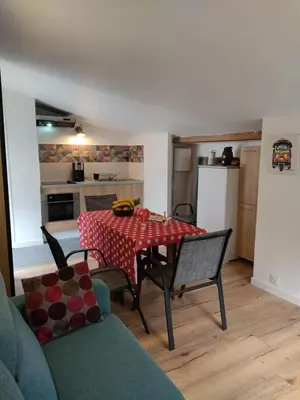 a living room with a table and chairs and a kitchen at Studio dans la forêt provençale in Jouques