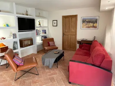 a living room with a red couch and a table at La Farigoulette - Vieux village in Saint-Saturnin-les-Apt